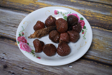 A simple serving of kelubi fruit on a plate decorated with flowers.