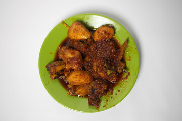 Spicy chicken served on a green plate, coated in a savory red chili sauce.