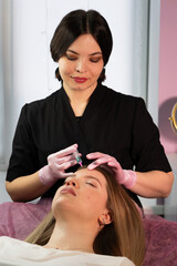 Aesthetician administering non-surgical forehead rejuvenation skincare. Biorevitalization peel for...