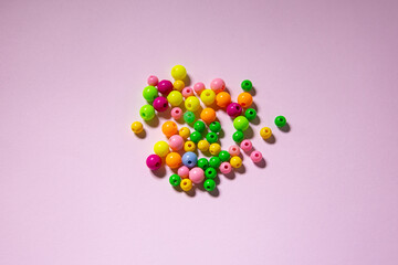 scattered multi-colored beads on a pink background, photo of beads