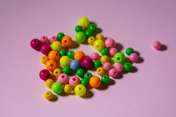 scattered multi-colored beads on a pink background, photo of beads