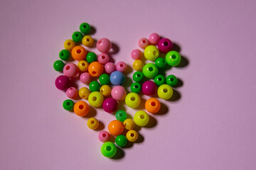 scattered multi-colored beads on a pink background, photo of beads