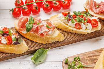 Tasty antipasto toasts featuring classic caprese with mozzarella and tomatoes, and savory prosciutto with herbs