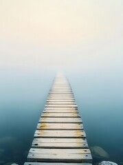 Misty wooden pier extending into calm water, surrounded by soft fog, serene atmosphere