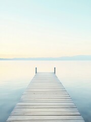 Serene wooden dock extending into calm waters at dawn, surrounded by distant mountains