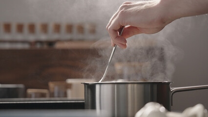 man hand stir fettuccine in boiling water in saucepan