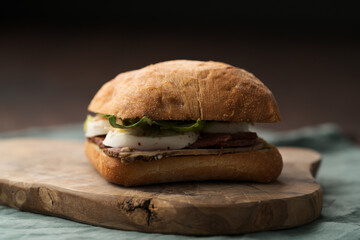 Roast beef and mozzarella sandwich with ciabatta bun on olive board