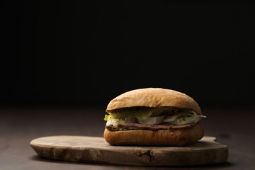 Roast beef and mozzarella sandwich with ciabatta bun on olive board