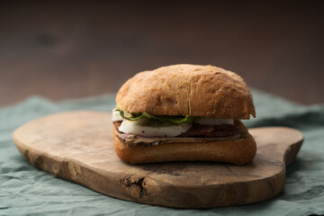Roast beef and mozzarella sandwich with ciabatta bun on olive board