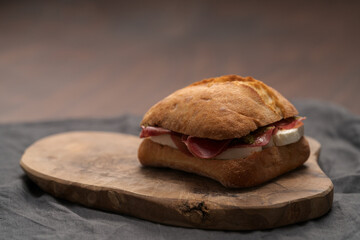 Sandwich with bresaola, mozzarella and pest on olive board