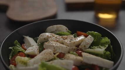salad with mozzarella and tomatoes in black bowl and apple cider in glass on concrete countertop