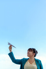 Businesswoman launching paper airplane into the sky, representing freedom, future and new opportunities