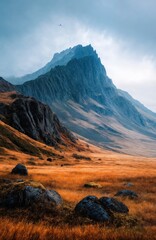Misty Cliffside Mountain Rising Above Golden Grass Hillside in Autumn Light, Dramatic Landscape with Steep Rocky Slopes, Rugged Nature Scene Evoking Solitude, Wilderness, and Majestic Elevation