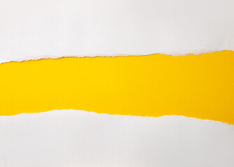 Hole ripped in white paper on yellow background.