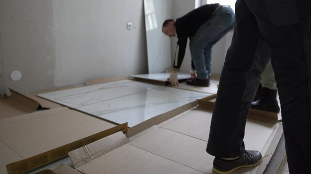 The craftsmen select the pattern on the tile for laying on the wall. Unpacking large-format porcelain tiles measuring 120 by 60 inches on the walls. High quality 4k footage
