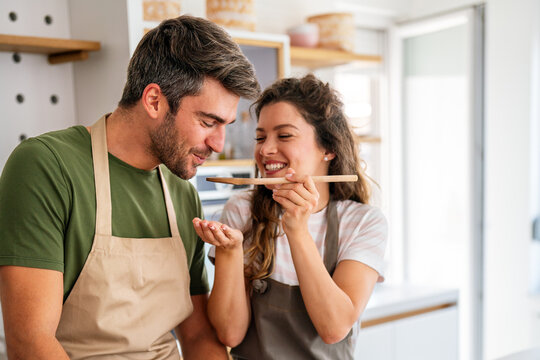 Happy couple enjoying cooking in the kitchen feeling happy and carefree on weekend lifestyle at home