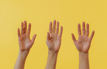 Obraz premium Raising Human Hands Against a Yellow Background