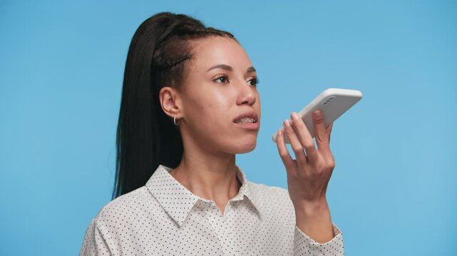 Woman using voice command or recording audio on phone on blue