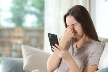 Woman using phone suffering eye strain at home