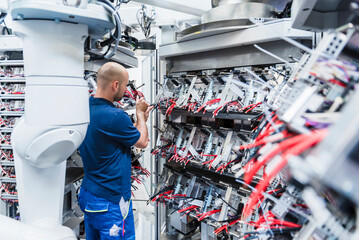 Technician repairing industrial robots in a production hall