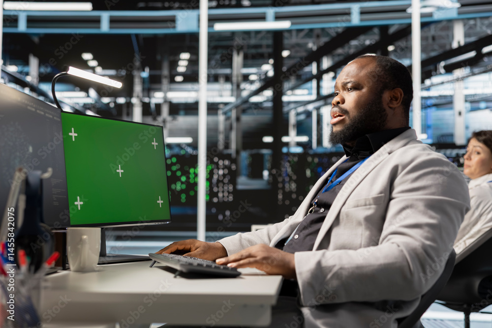Poster server hub engineer looking at data visualization on green screen pc to pinpoint equipment performan