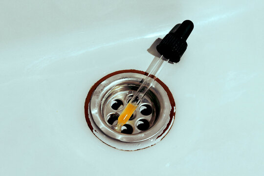 Closeup of a vitamin C serum dropper on a sink with retro aesthetics