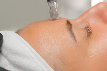 Microneedle RF lifting procedure. A cosmetologist performs a facial rejuvenation procedure on a...
