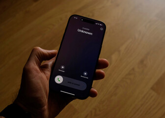 Fraud or fraudulent schemes. Close-up of a male hand holding a phone with an unexpected incoming...