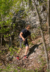 Naklejka premium Man hiking up forest slope