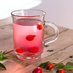 rose hips tea in glass cup on wooden background