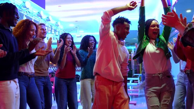 Enthusiastic friends dancing and clapping at roller disco