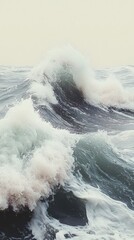 Powerful ocean waves crashing on the shore, creating a foamy white spectacle against a muted pastel background