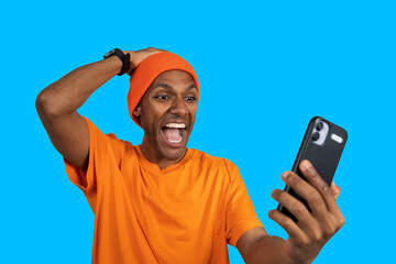 Excited man celebrating success on smartphone with blue background