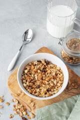 Homemade baked granola or muesli in a bowl on a wooden board on a light background