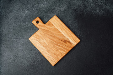 Wooden cutting board placed on a dark surface in a kitchen setting