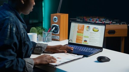 Entrepreneur working from home, using laptop, writing notes on paper. Remote worker in personal...