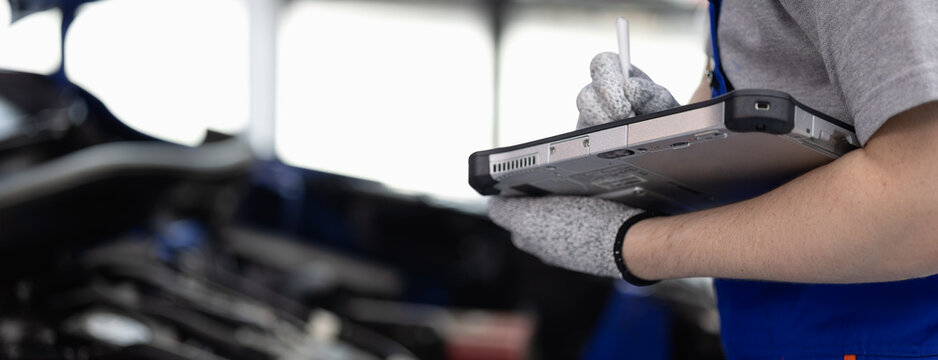 Panoramic close-up hand of Professional mechanic holding the tablet for maintenance checklist vehicle, Software for manager check to repair