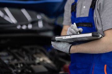 Close-up hand of Professional mechanic holding the tablet for maintenance checklist vehicle, Software for manager check to repair