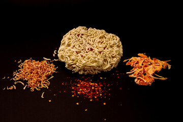 Raw ingredients for ramen noodles preparation - round-shaped wheat noodles surrounded by dehydrated...