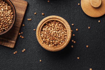 Buckwheat grains in a wooden container on a dark surface