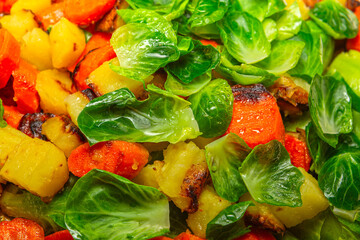 Top-down view of colorful vegetable mix frying in oil with brussel sprouts opening their leaves, carrots softening and crisping potatoes.