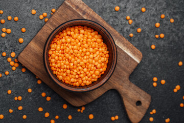 Vibrant orange lentils in a wooden bowl on a cutting board