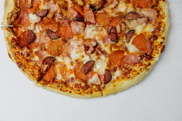 Delicious pizza topped with pepperoni and sausage on a white surface