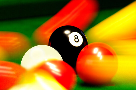 Close-up of a game of pool with the red balls moving around the white and black ball