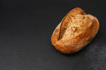 Freshly baked artisanal bread resting on a dark surface for display