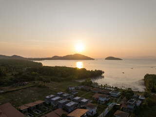 Serene Coastal Village Under Setting Sun with Islands in the Background