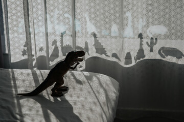 Nursery room with dinosaur shadows on curtain.