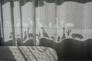 Nursery room with dinosaur shadows on curtain.