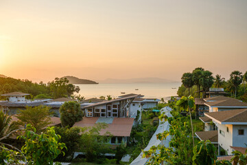 Serene Coastal Village Under Setting Sun with Islands in the Background