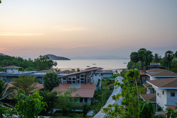 Serene Coastal Village Under Setting Sun with Islands in the Background